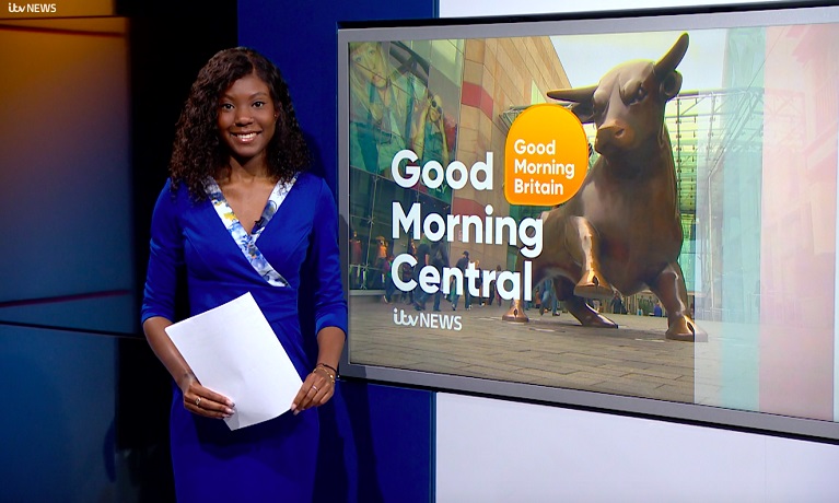 Graduate Monifa Bobb-Simon standing in front of a Good Morning Central TV screen with script in her hand.