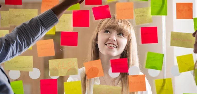 Girl looking at post it notes on a clear board