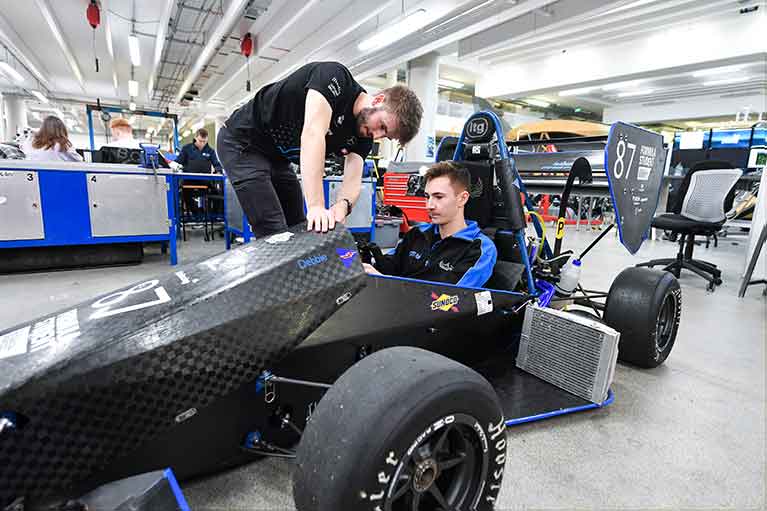 two students examining a motorsport car at Coventry Univeristy