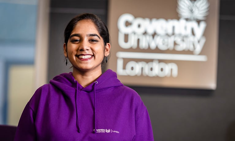 Dominica stood in front of Coventry University London sign.