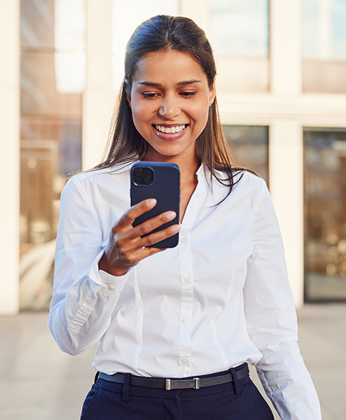 woman smiling at her phone outside of an office building