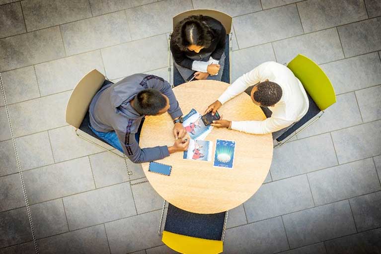 three people having a meeting around the small round table