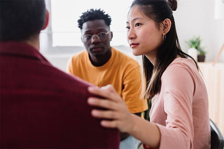 shot of a woman holding a mans shoulder in a therapy session