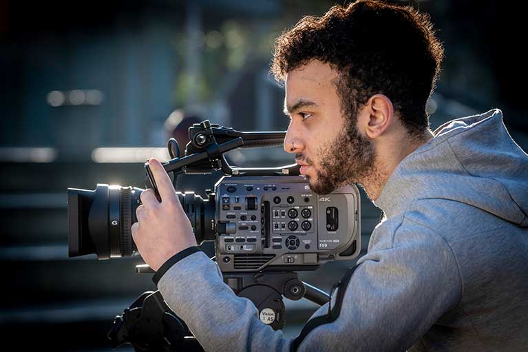 a student adjusting a film camera