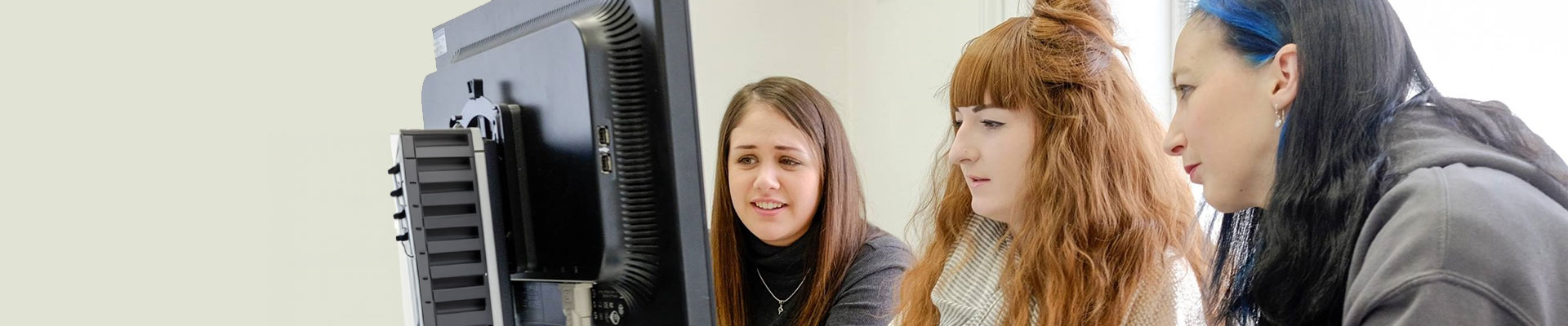 Students and tutor working at a desktop computer