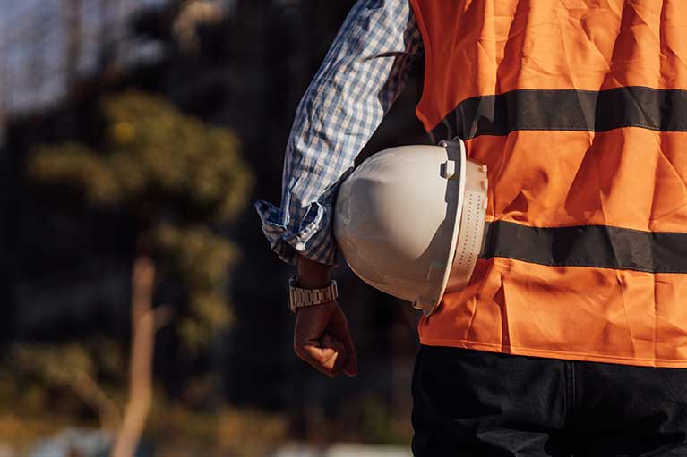 picture of a construction worker in a high-vis vest overlooking a construction site