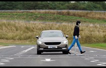 A mannequin crossing a road in front of a car 