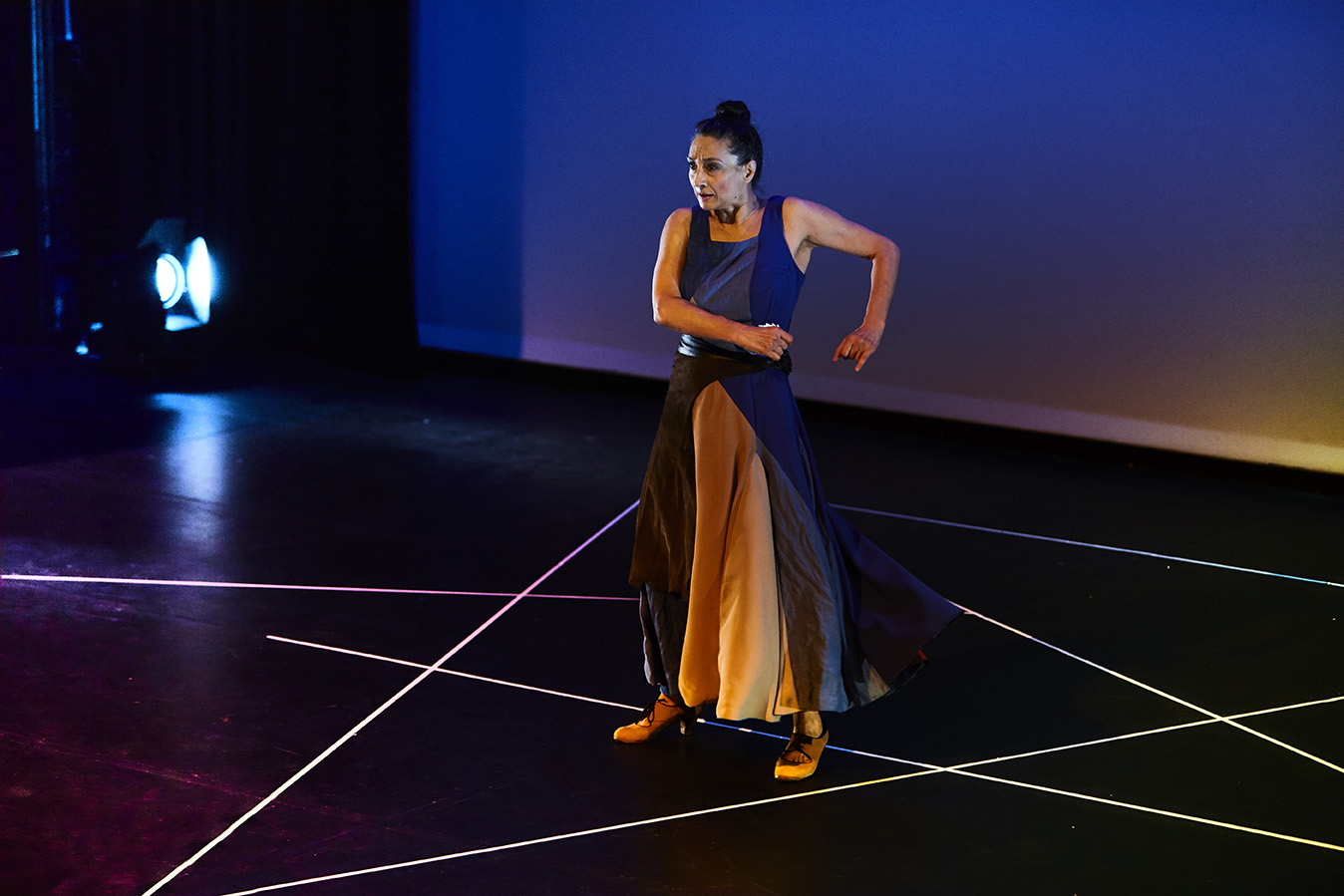 A woman performing on stage with stage lights and a screen in the background