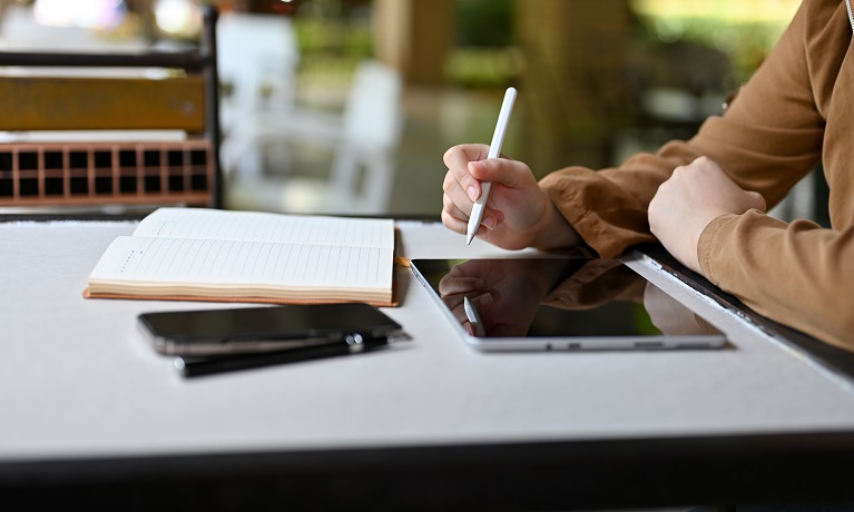 A female student sitting in the library using a digital tablet