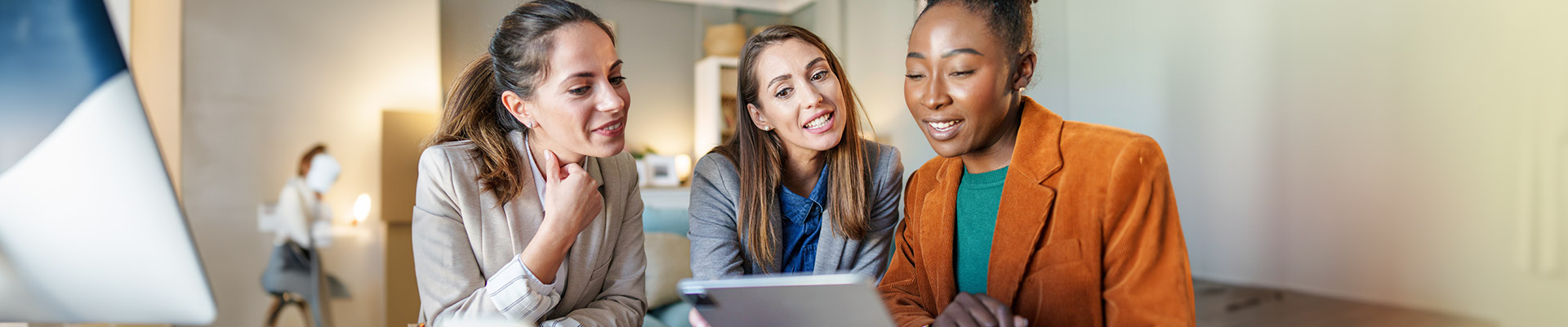 three women looking at a computer tablet