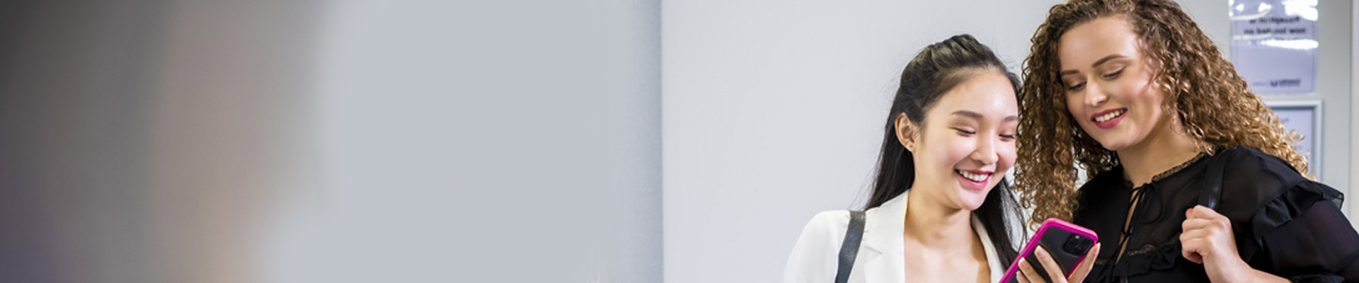 two girls looking at a phone and smiling