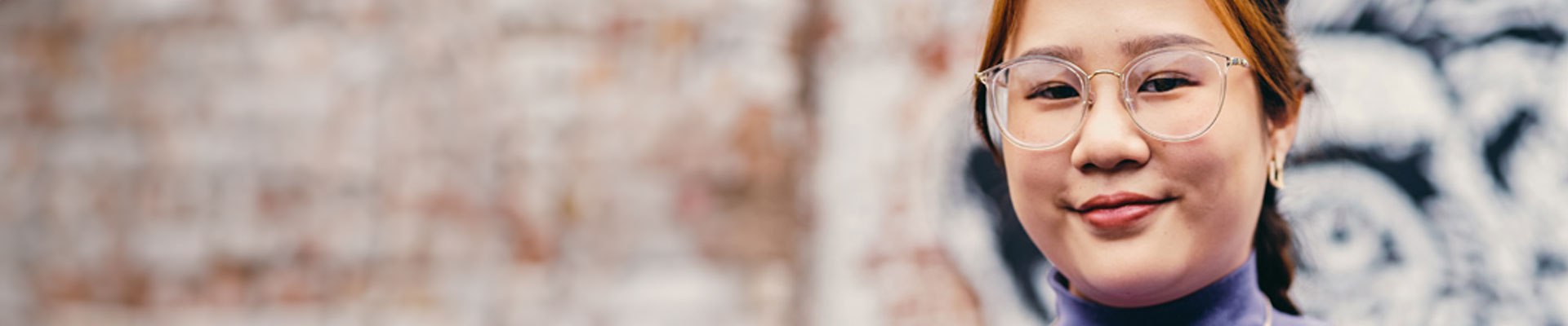 Student posing for the camera infront of a graffit wall