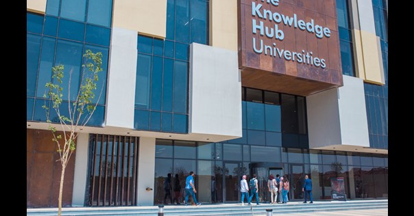 People walking into the Egypt Knowledge Hub, a modern glass fronted building.