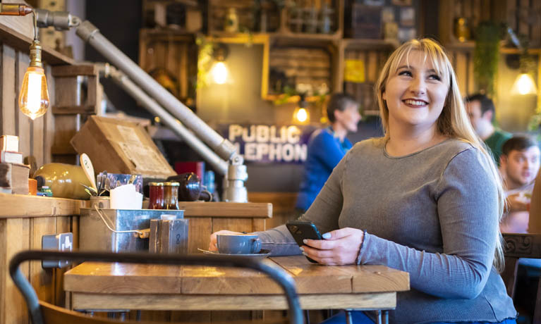 Three students socialising at a table outside a bar