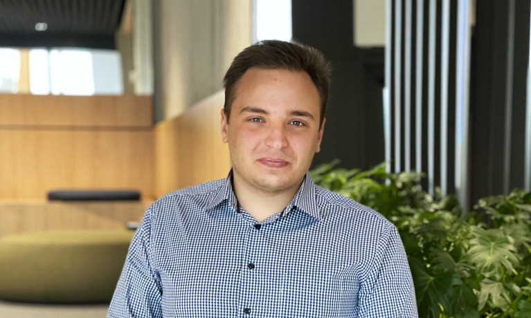 A headshot of Alexander with plants behind him.