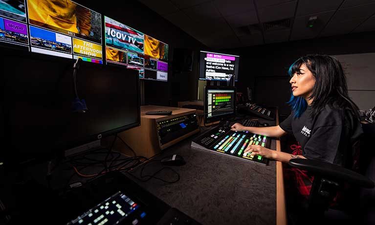 Student working in front of a bank of colourful screens