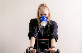 Student using exercise bike and breathing measurement equipment.