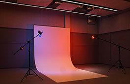 Photography studio with a white background, coloured lights and equipment around