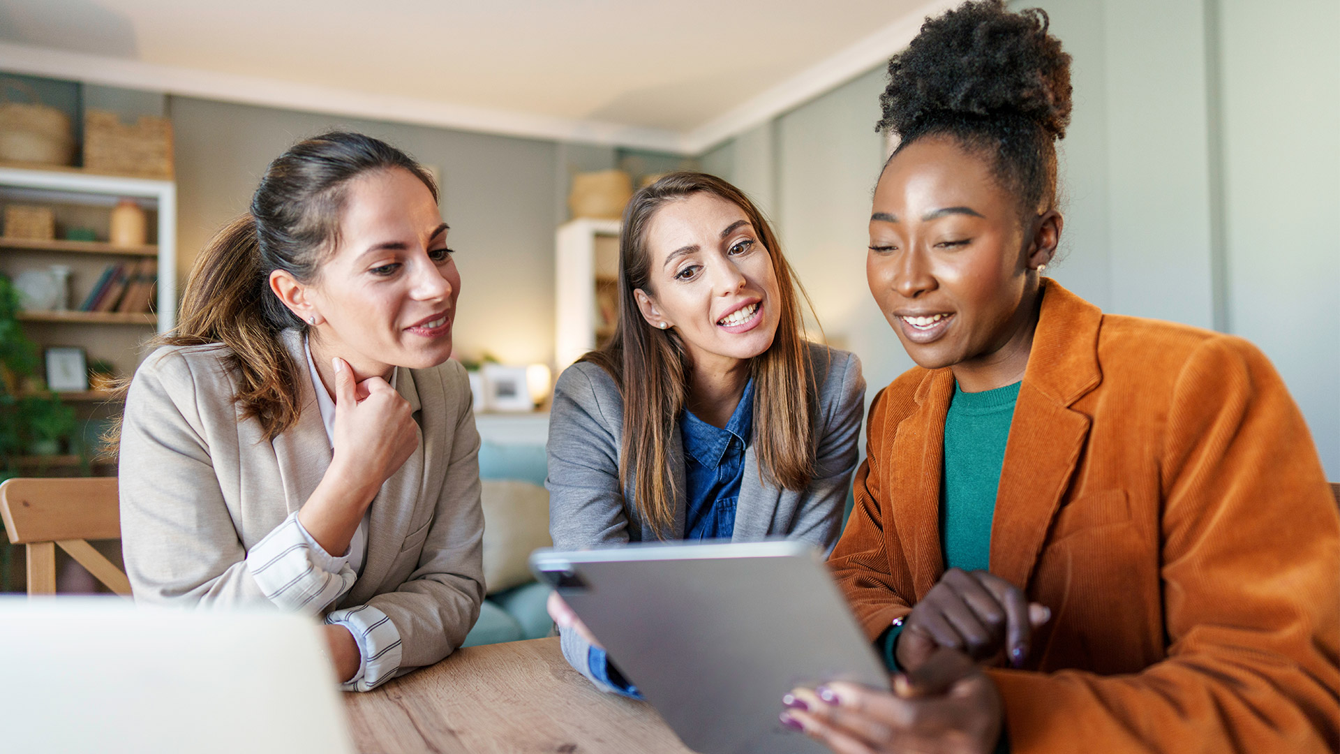 three women looking at an ipad