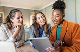 three women looking at an ipad