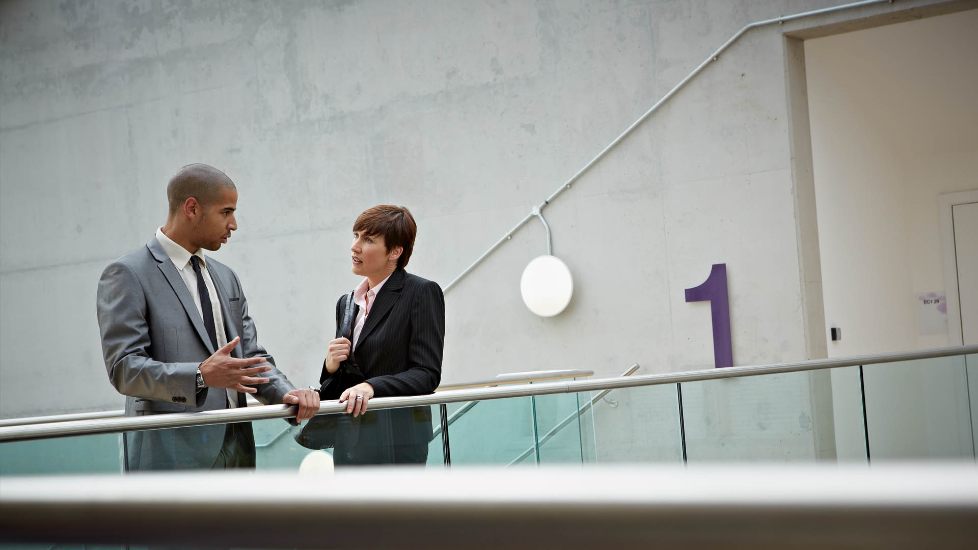 Two professionally dressed people talking in a hallway