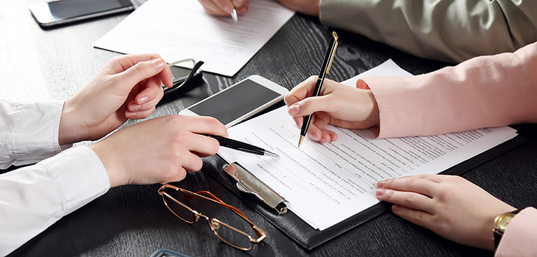 one person takes notes as another person points to the notes with their pen