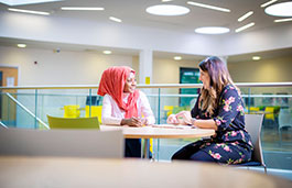 Two students sit on the seats and talk happily.