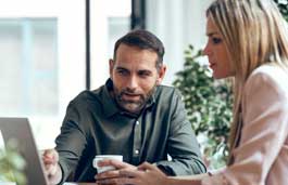Two people look at a laptop screen together