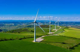A row of wind turbines in a field with a blue sky