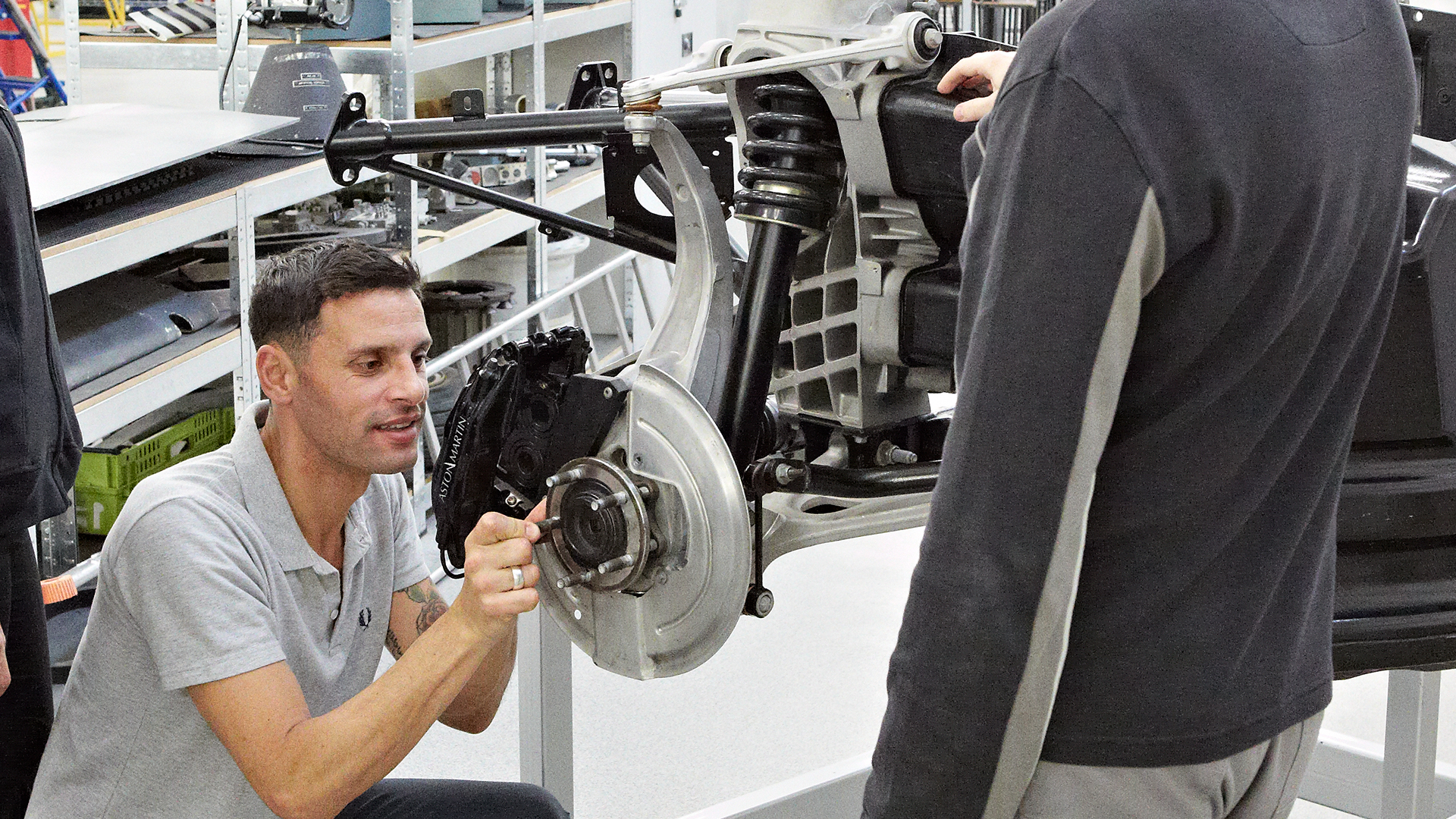 A man in a grey t shirt working on an engine.