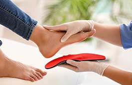 A podiatrist fitting an insole holding the patients foot 