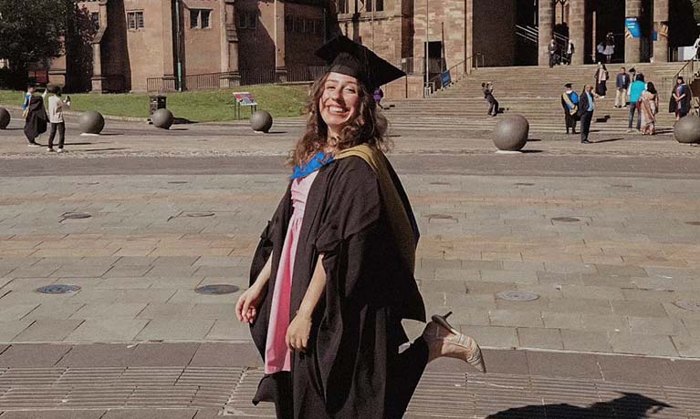 Sonia wearing her graduation gown outside Coventry cathedral