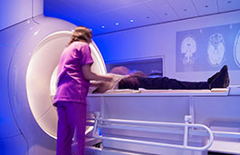 female in scrubs preparing a patient who is lying down in a CT scanning machine