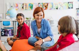 A teacher with two children, she is turned smiling at one of them