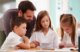 A teacher helping young schoolchildren with their reading.