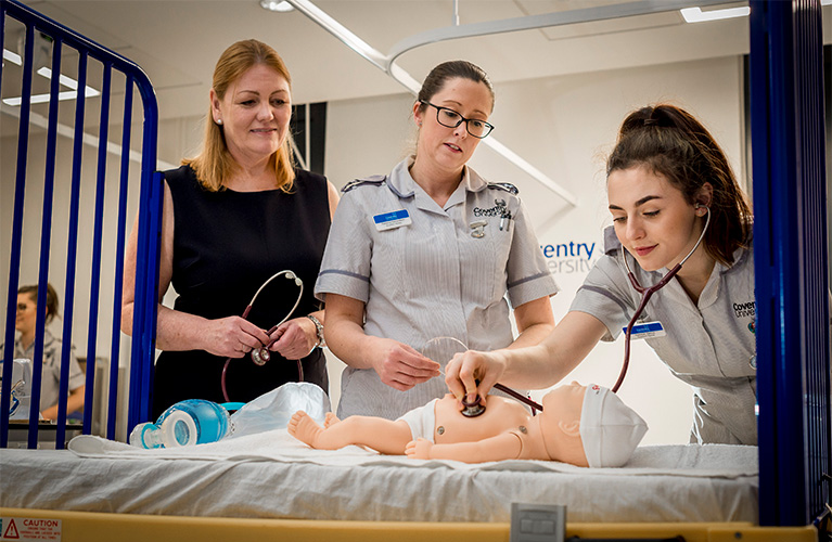 Two students and a staff member working on a baby mannequin
