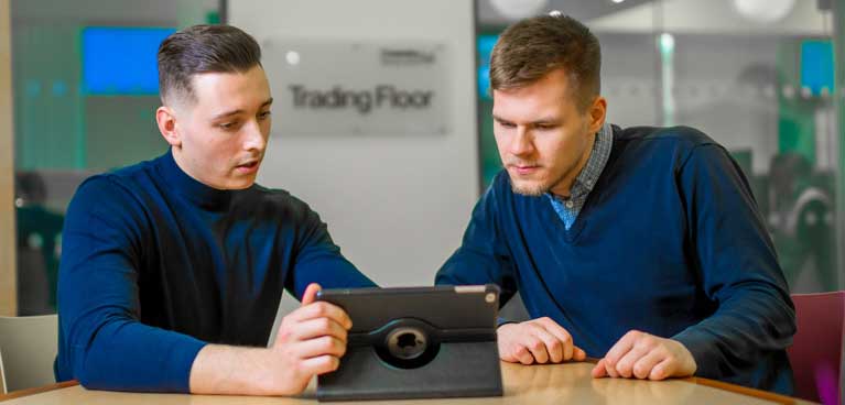 Two students sat at desk looking at iPad.