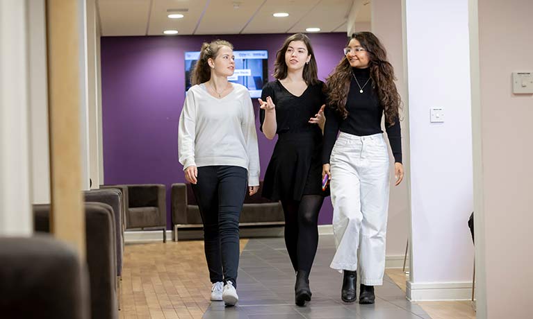 Three students walking down a corridor