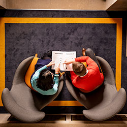 Aerial view of two people sitting round a table looking at a document