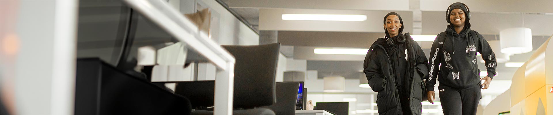 Two students walking through The Hub whilst talking