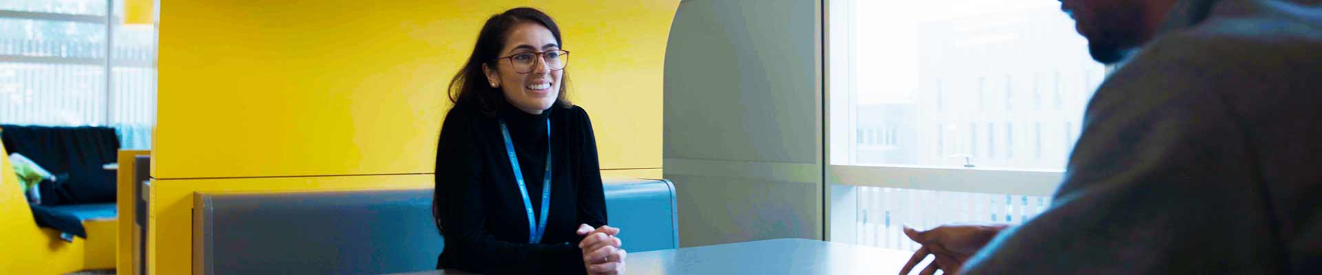 A female wearing a lanyard facing a male across a table