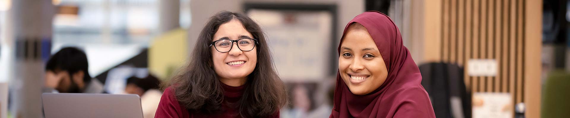 Two students in the courtyard smiling