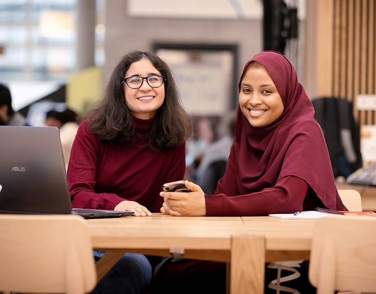 Two students in the courtyard smiling