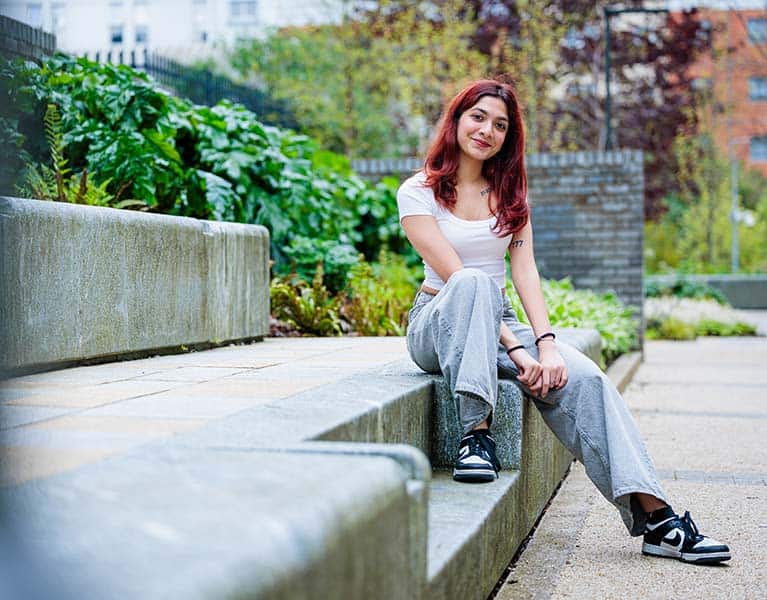 A student sitting outside in the campus grounds