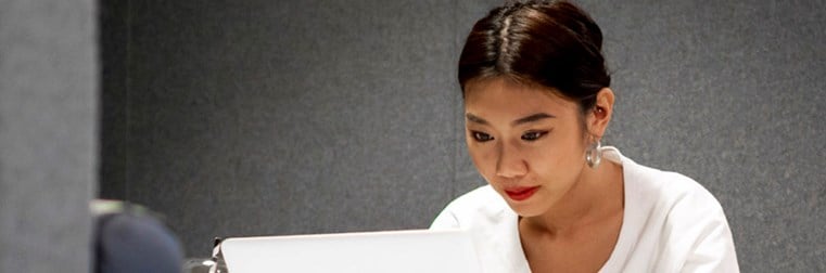 A woman working on a laptop in a study area on campus.