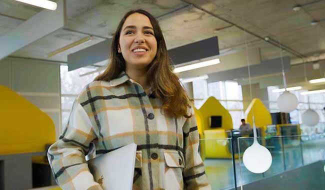 Female in plaid shirt holding a laptop