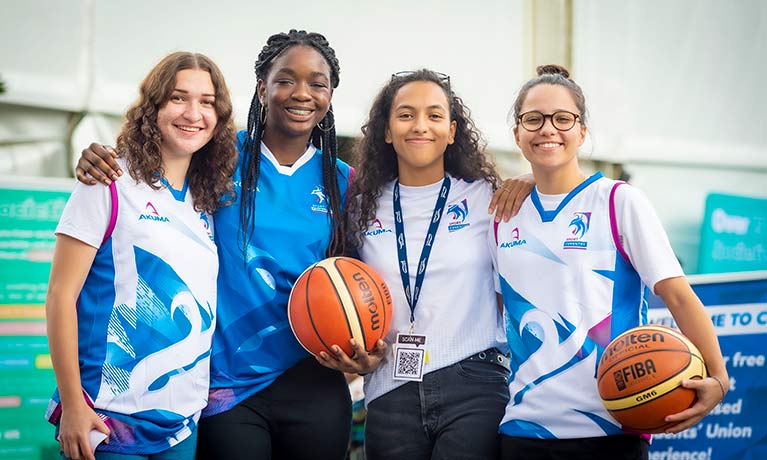 4 young females in sports clothes smiling looking at the camera 