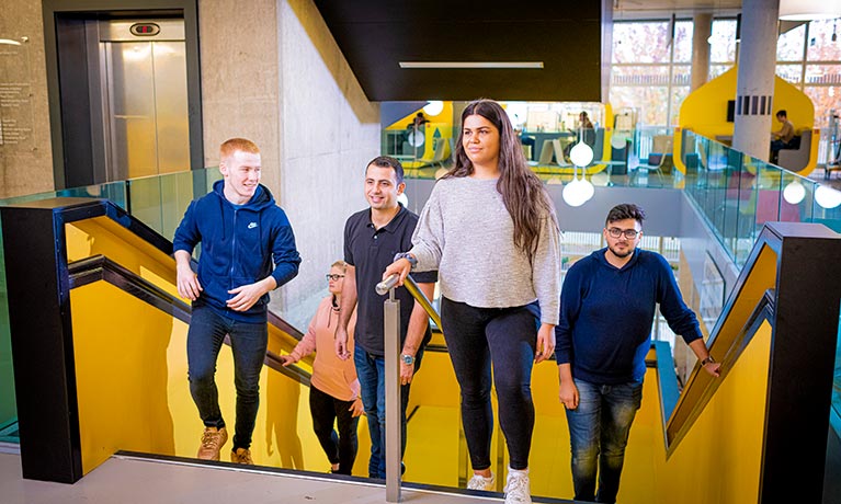 group of students walking up a large yellow staircase