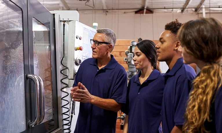 Apprentices looking at a cabinet with glass doors with technology inside