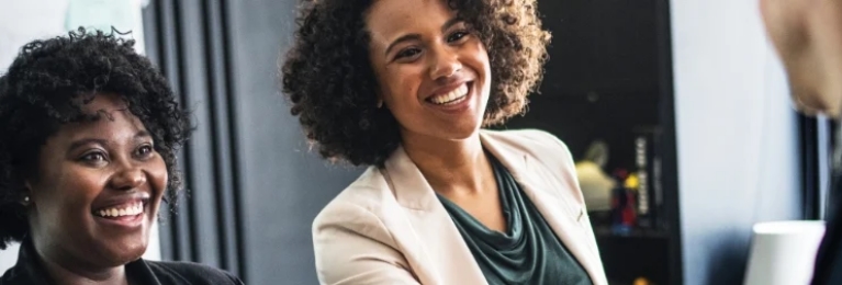 Two women smiling while looking towards the side